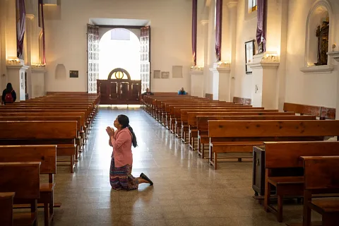 Kvinne som ber i en kirke