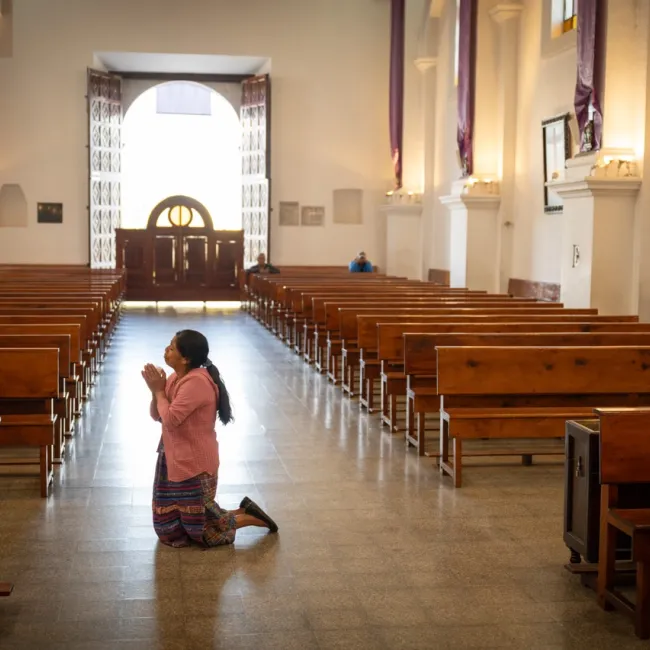 Kvinne som ber i en kirke